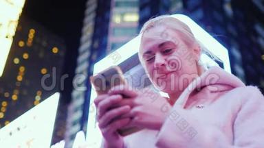 纽约时代广场。 夜晚摩天大楼背景下一位年轻白种人妇女的肖像。 微笑享受